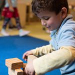 Young student playing with building blocks