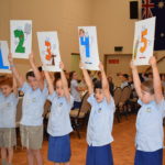 Students holding up number signs in the main hall